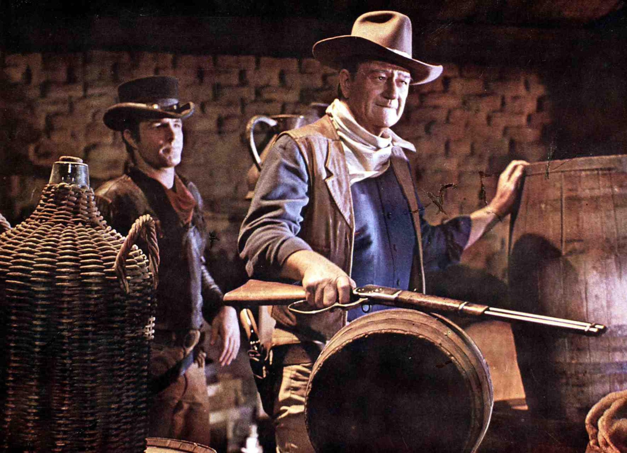 'El Dorado' James Caan as Mississippi and John Wayne as Cole Thornton wearing Western outfits surrounded by barrels
