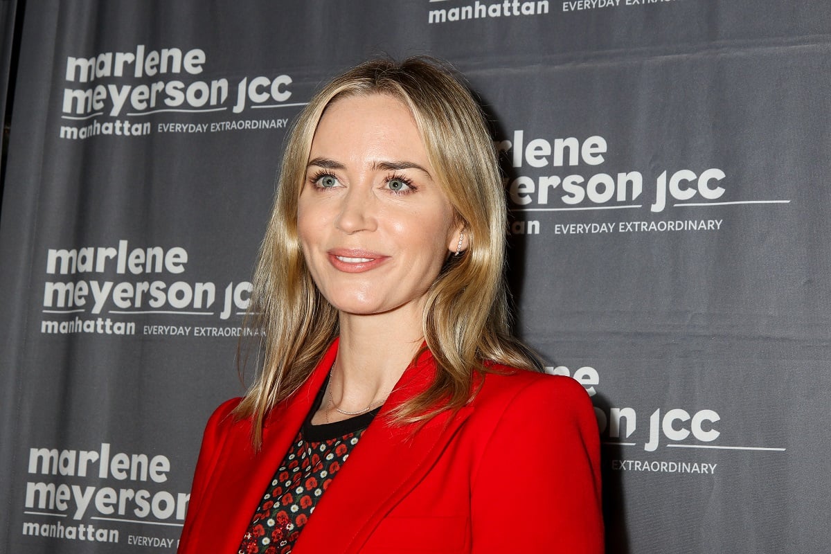 Emily Blunt smiling while wearing a red dress.