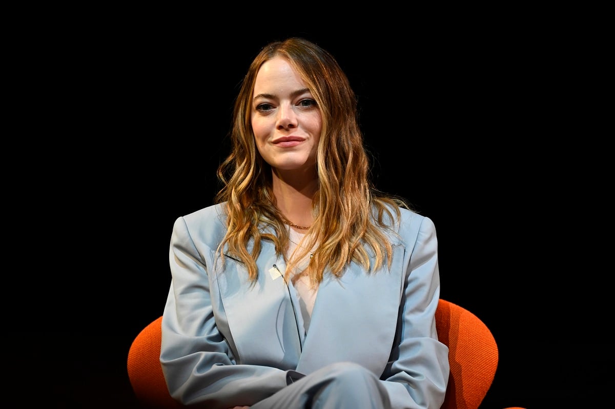 Emma Stone sitting down while wearing a blue outfit.