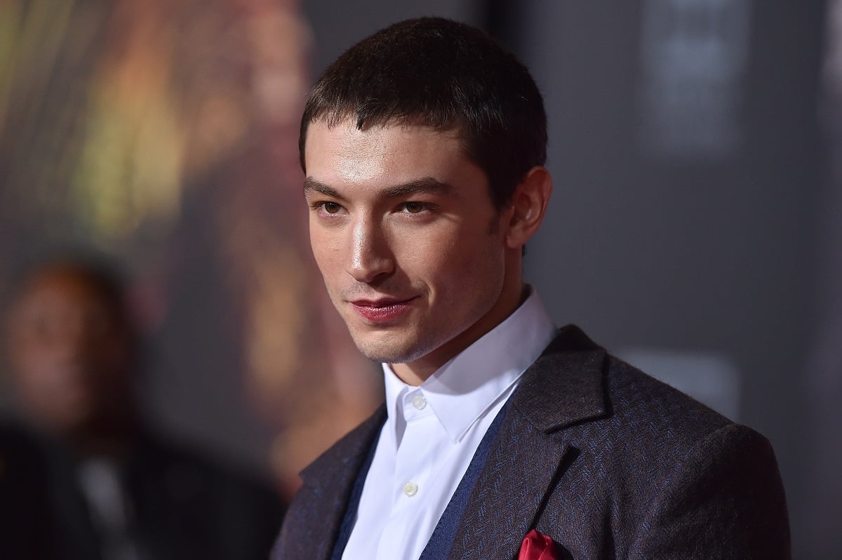 Ezra Miller smirking while wearing a suit.