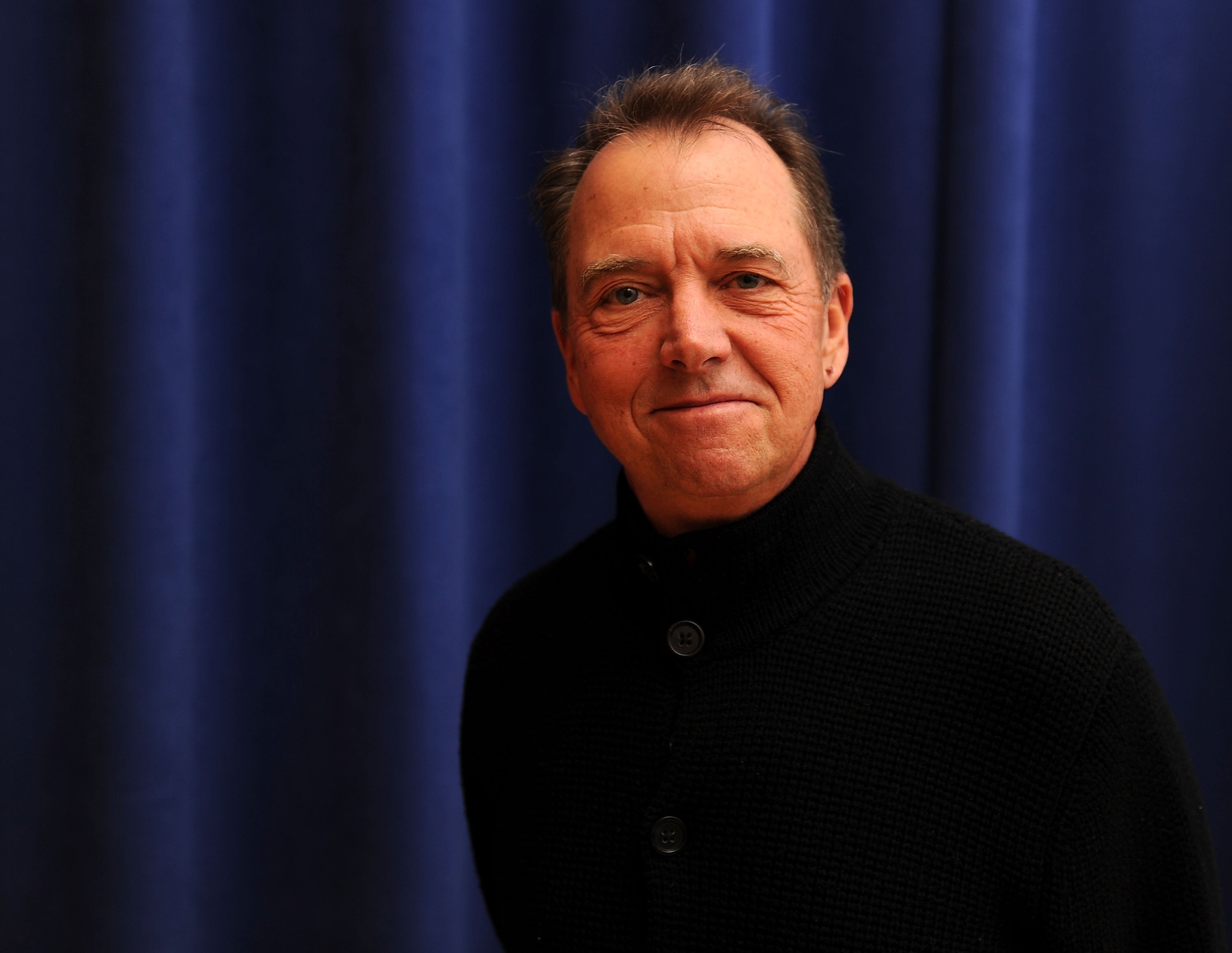 Gregory Itzin poses for a picture while wearing a black turtleneck.