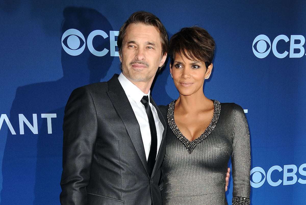 Halle Berry and Olivier Martinez standing in front of a blue background