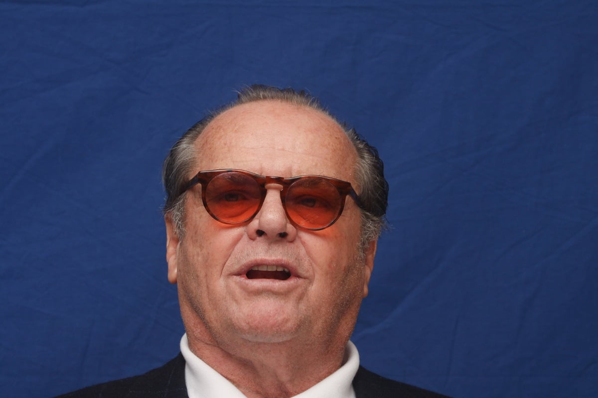 Jack Nicholson sitting down while wearing sunglasses and a suit.