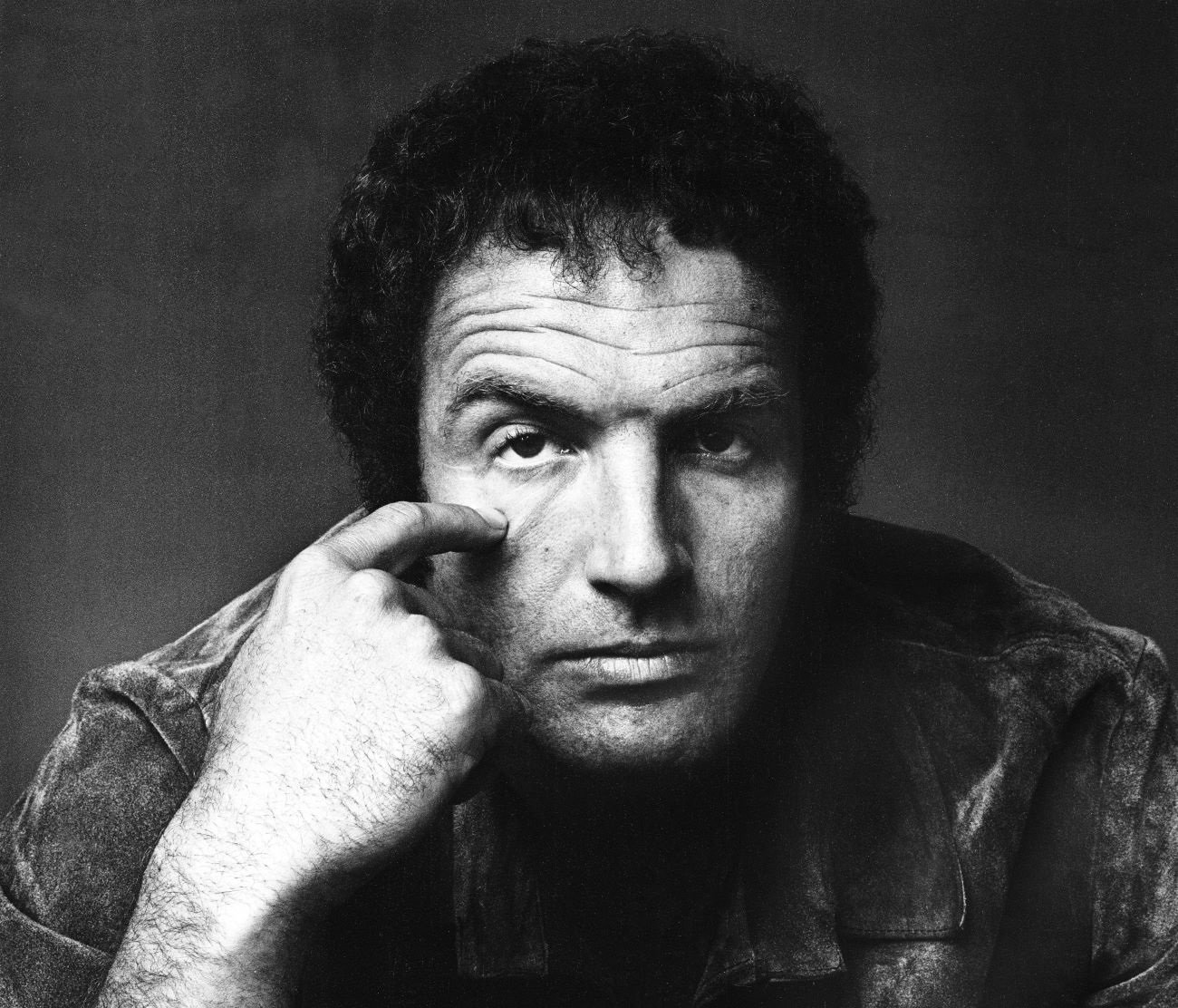 A black and white picture of James Caan with his finger touching his cheek.
