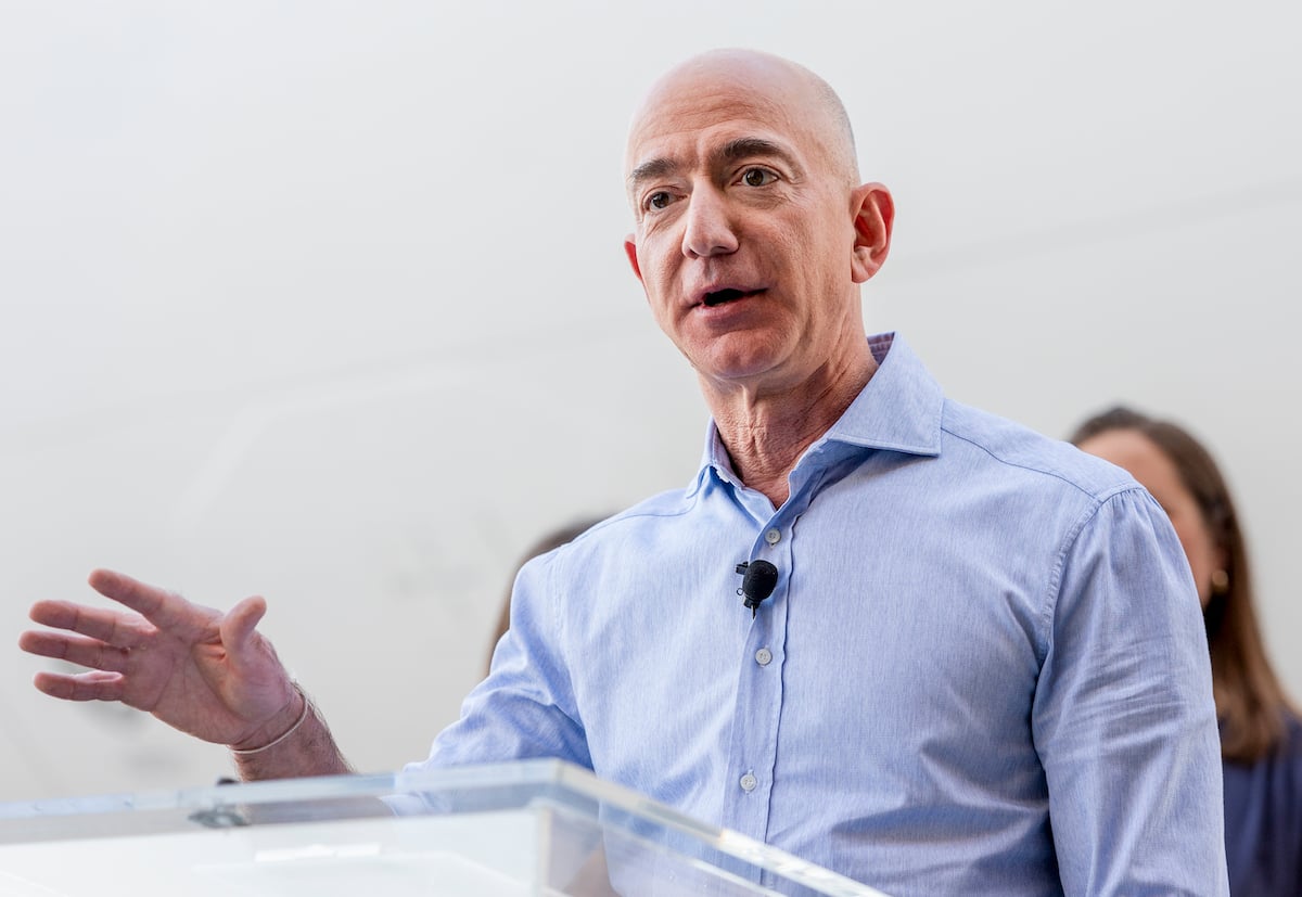 Jeff Bezos speaks at a white podium during an event.
