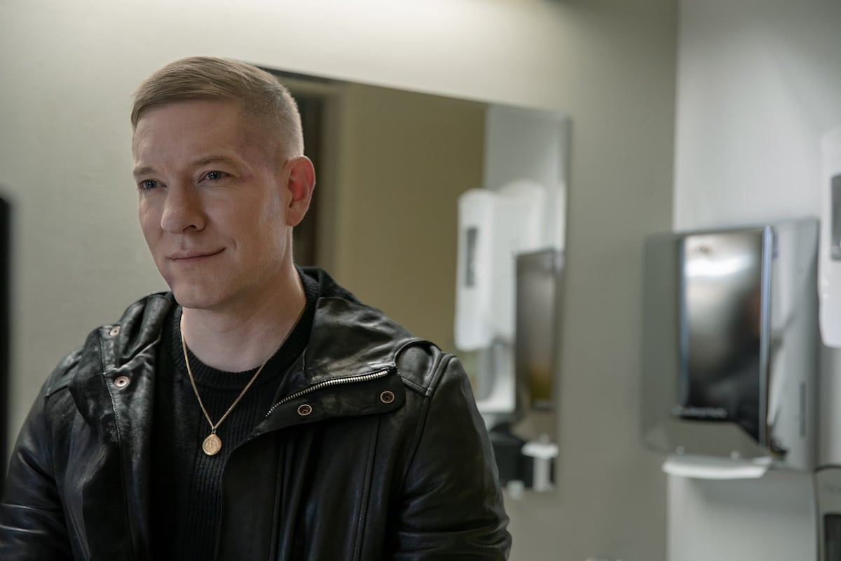 Joseph Sikora as Tommy Egan in 'Power Book IV: Force' wearing a leather jacket and gold chain while smirking