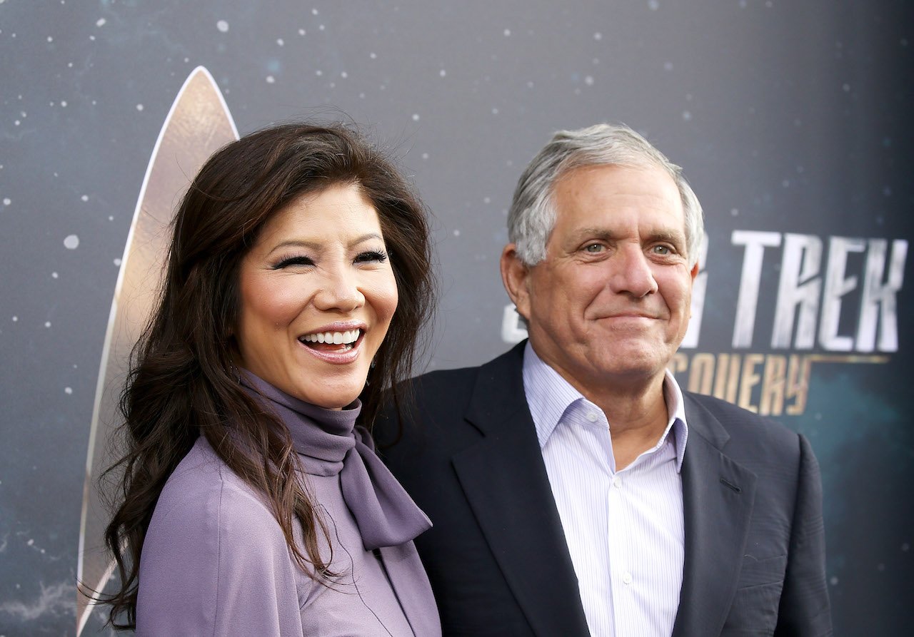 Julie Chen Moonves in a purple bow shirt stands next to Leslie Moonves who wears a black jacket and matching shirt.