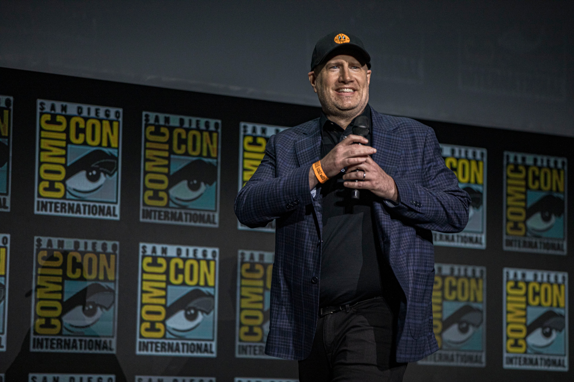 Marvel Studios president Kevin Feige at San Diego Comic-Con, where he announced Marvel's Phase 5 lineup. He's holding a microphone and wearing a baseball cap.