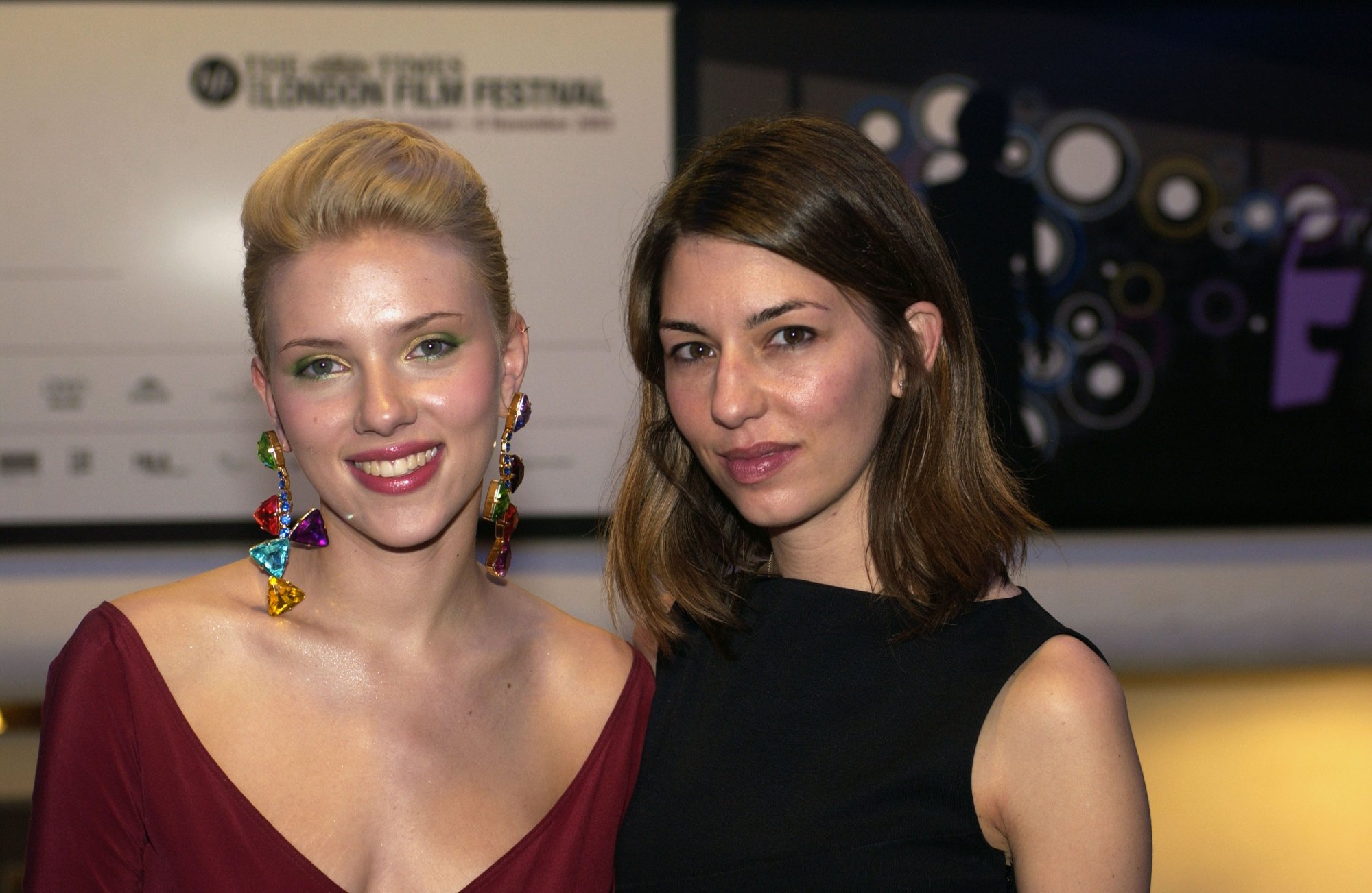 'Lost in Translation' Scarlett Johansson and Sofia Coppola smiling in red and black dresses in front of BFI London Film Festival sign