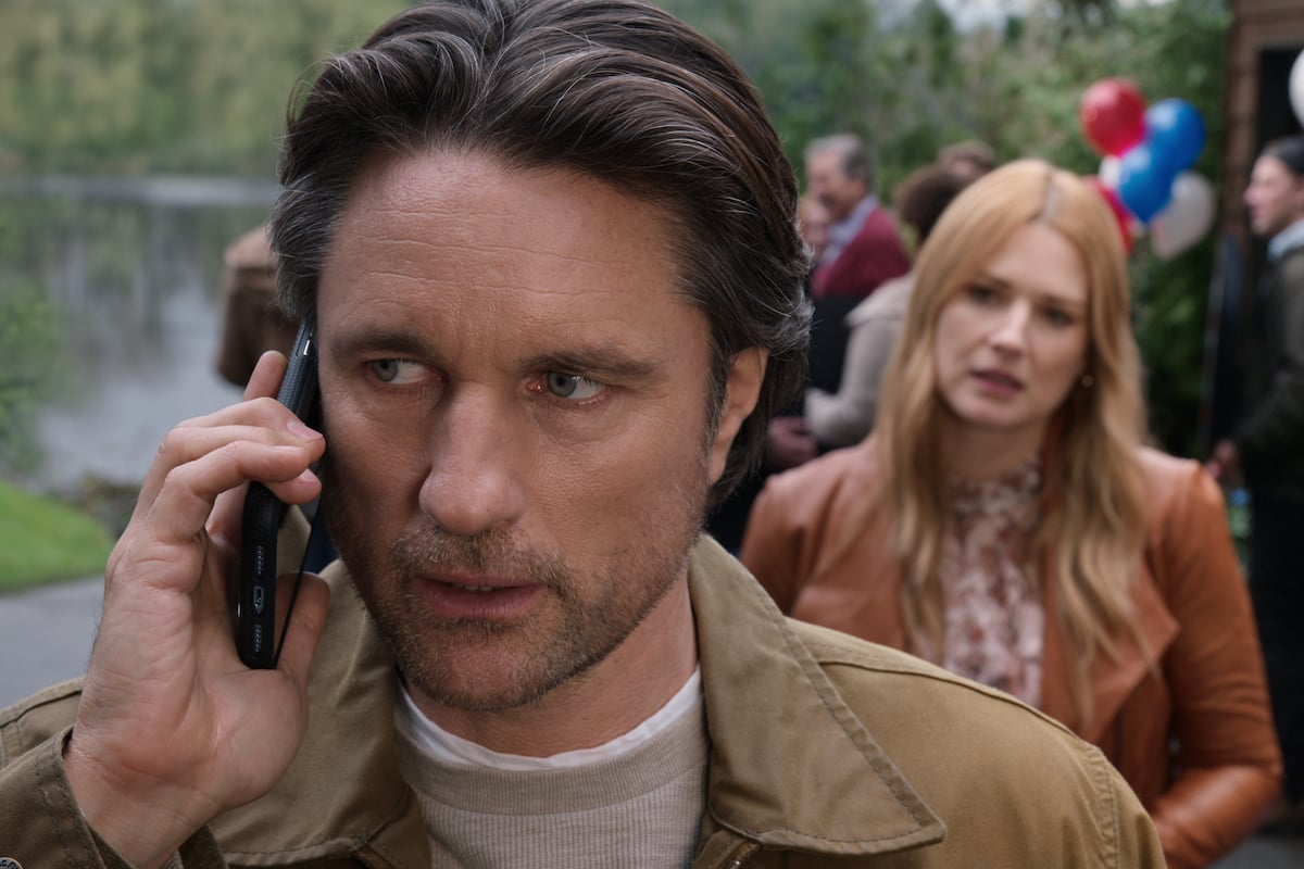 Martin Henderson as Jack Sheridan looking worried on the phone Alexandra Breckenridge as Mel Monroe listening in the background in 'Virgin River'