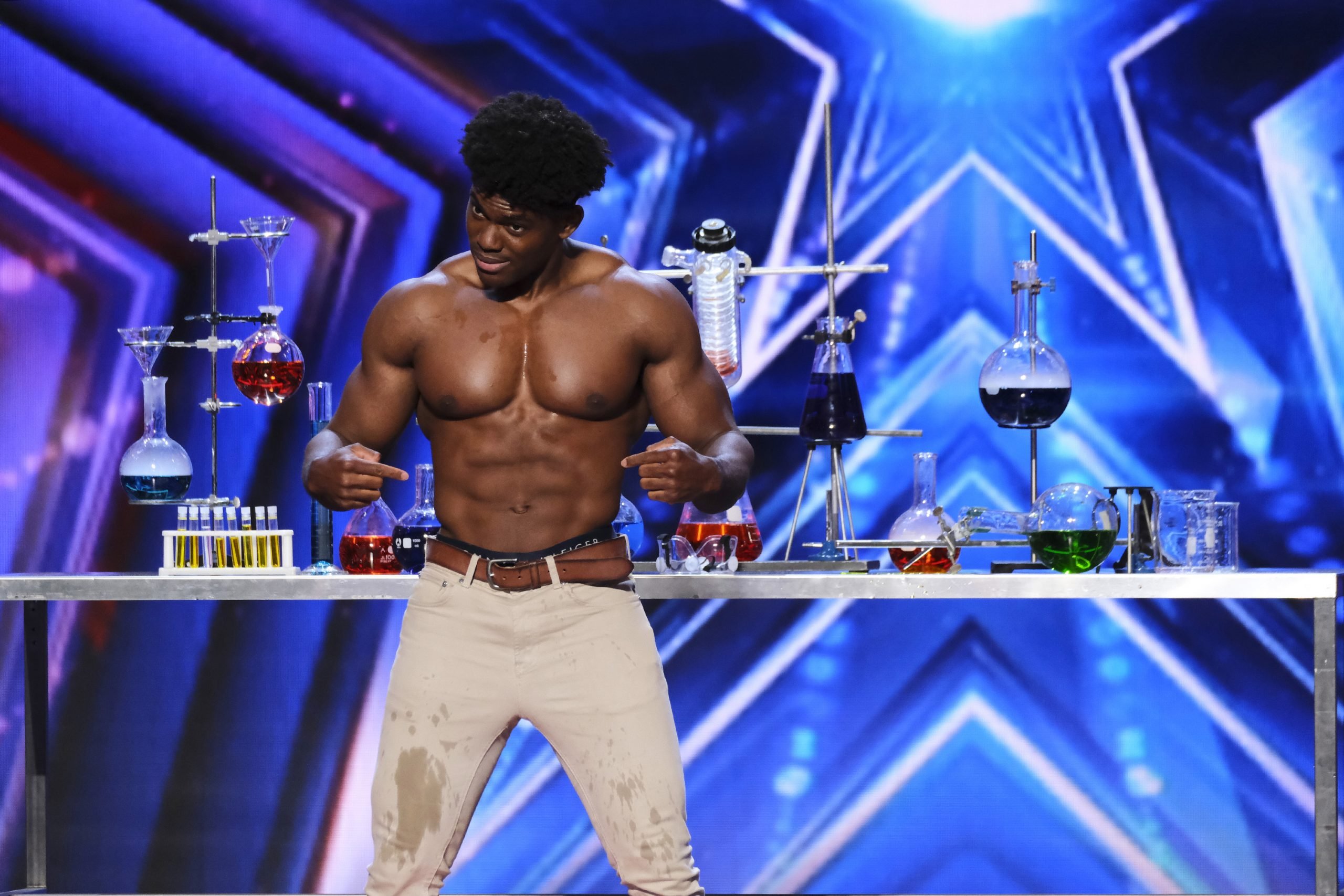 Marvin Achi with his shirt off pointing to his abs in an audition for 'America's Got Talent' Season 17