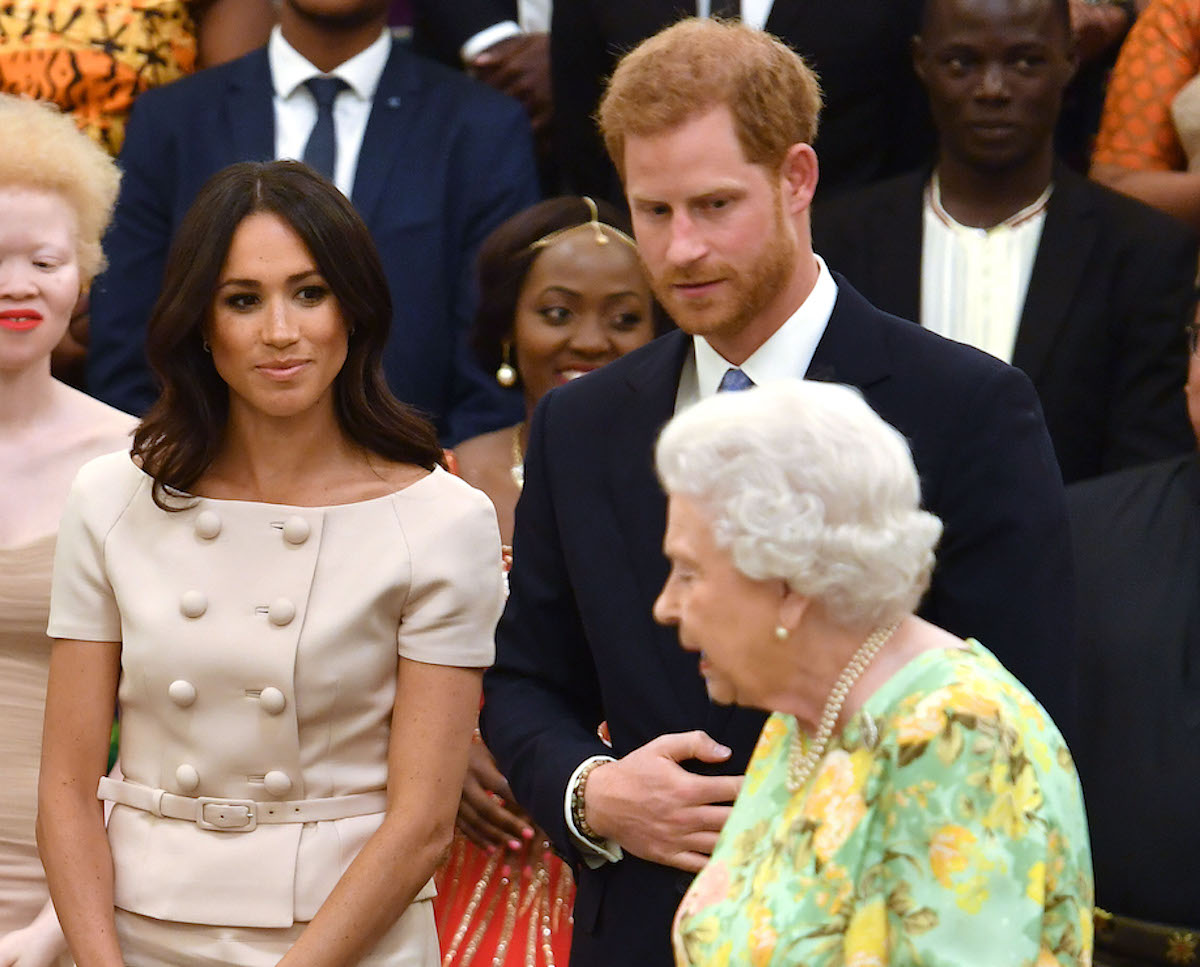 Queen Elizabeth, who reportedly visited Meghan Markle and Prince Harry at Frogmore Cottage, stands with Meghan Markle and Prince Harry