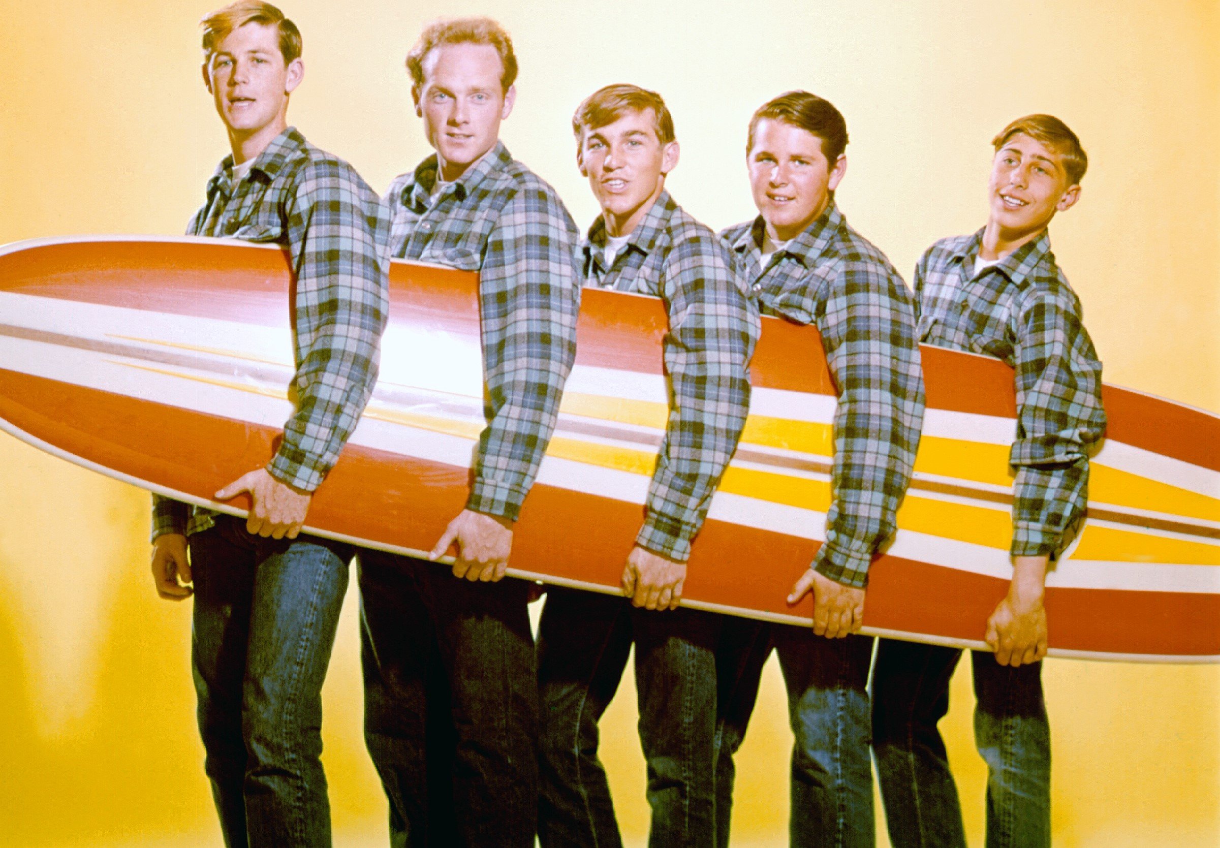 The Beach Boys holding a surf board