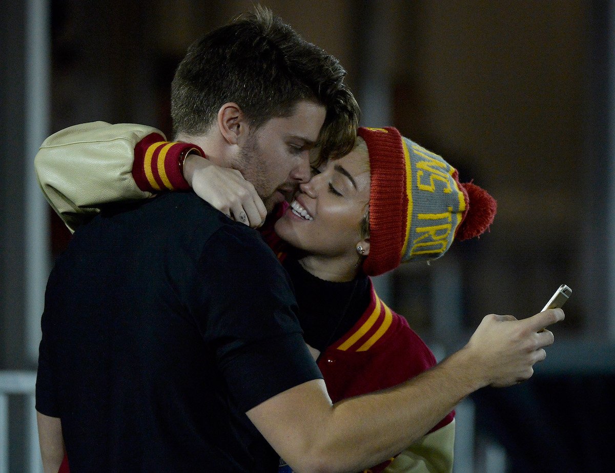 Miley Cyrus kisses Patrick Schwarzenegger during a USC football game in 2014