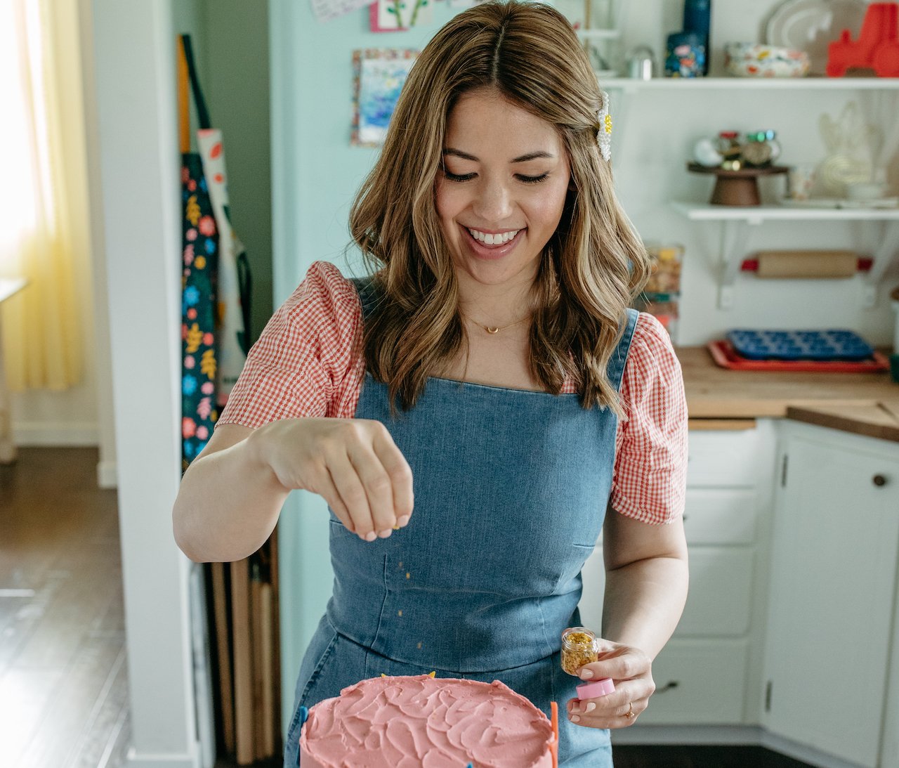 Chef Molly Yeh sprinkles a cake in a promotional photo for her new 'Girl Meets Farm' cookware line