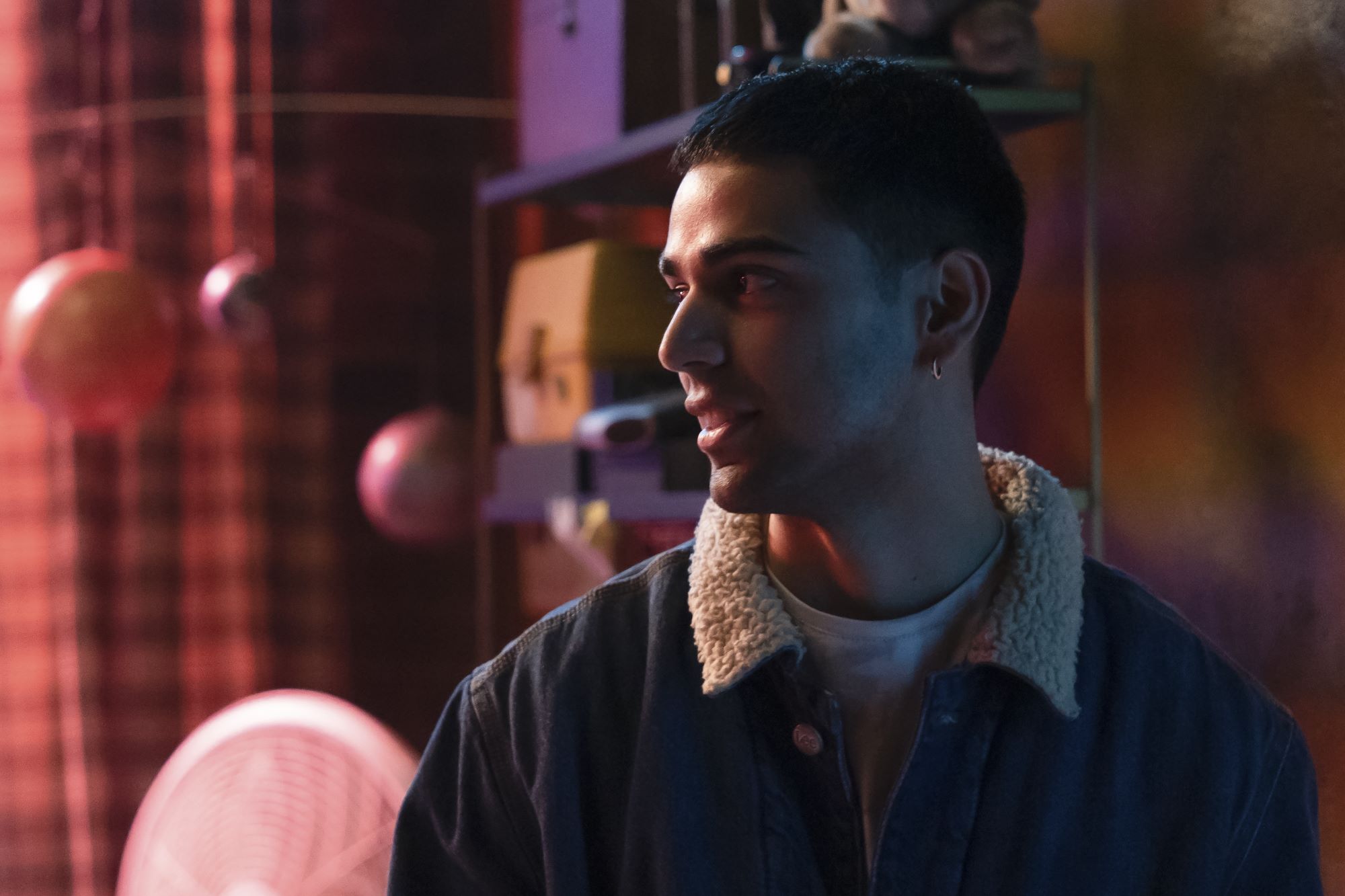 Rish Shah, in character as Kamran in 'Ms. Marvel' Episode 4, wears a jean jacket with a sherpa-lined collar over a white shirt.