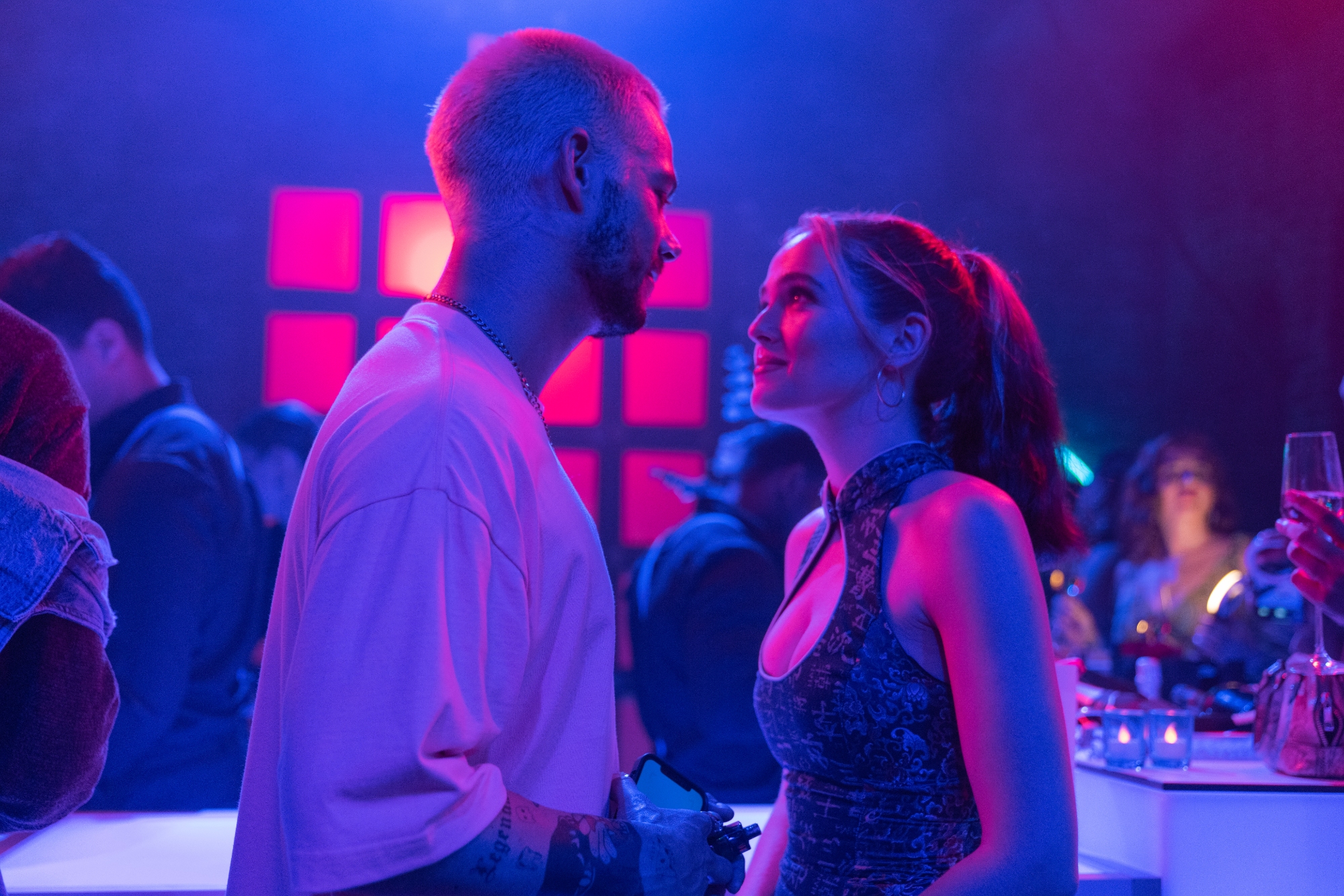 'Not Okay' Dylan O'Brien as Colin and Zoey Deutch as Danni Sanders looking into each other's eyes in front of a bar with neon purple lighting