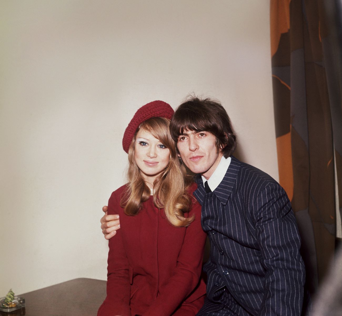 George Harrison holds his arm around his first wife Pattie Boyd's shoulders. She wears a knit hat.