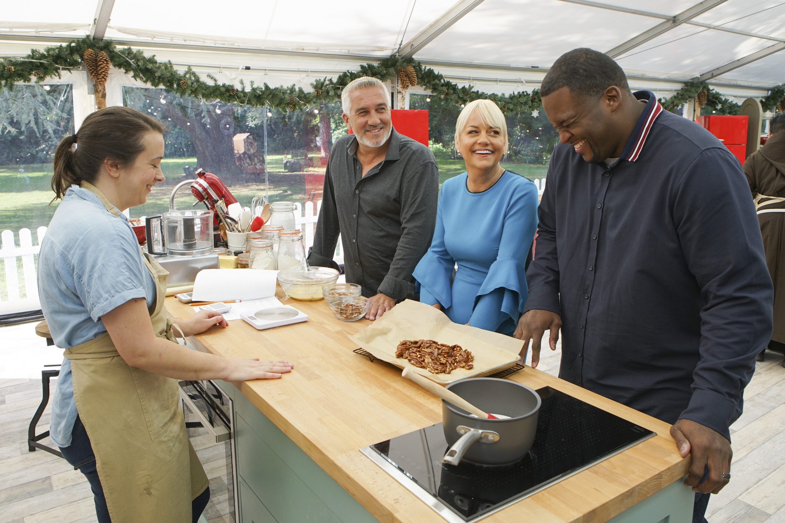 Contestant Marissa smiles at her baking station while Paul Hollywood, Sherry Yard and Anthony 'Spice' Adams laugh on 'The Great American Baking Show'
