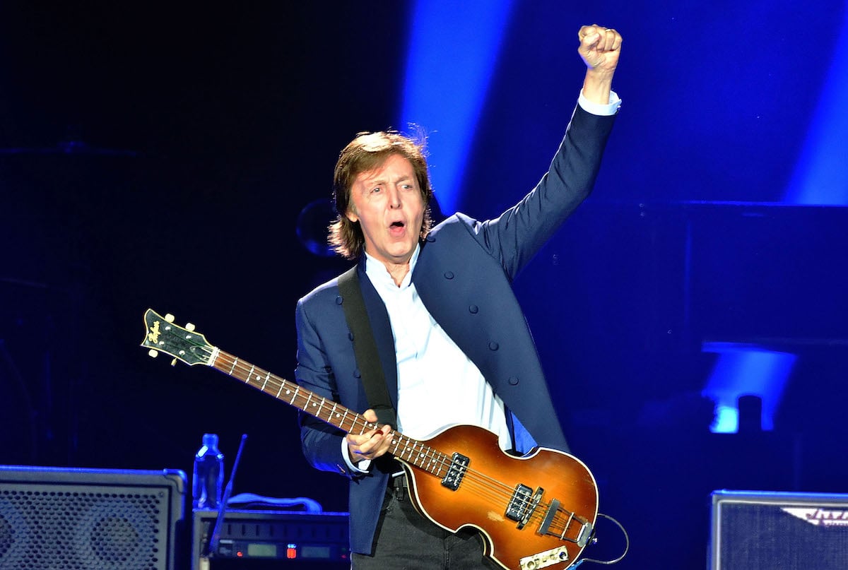 Paul McCartney plays the guitar on stage.