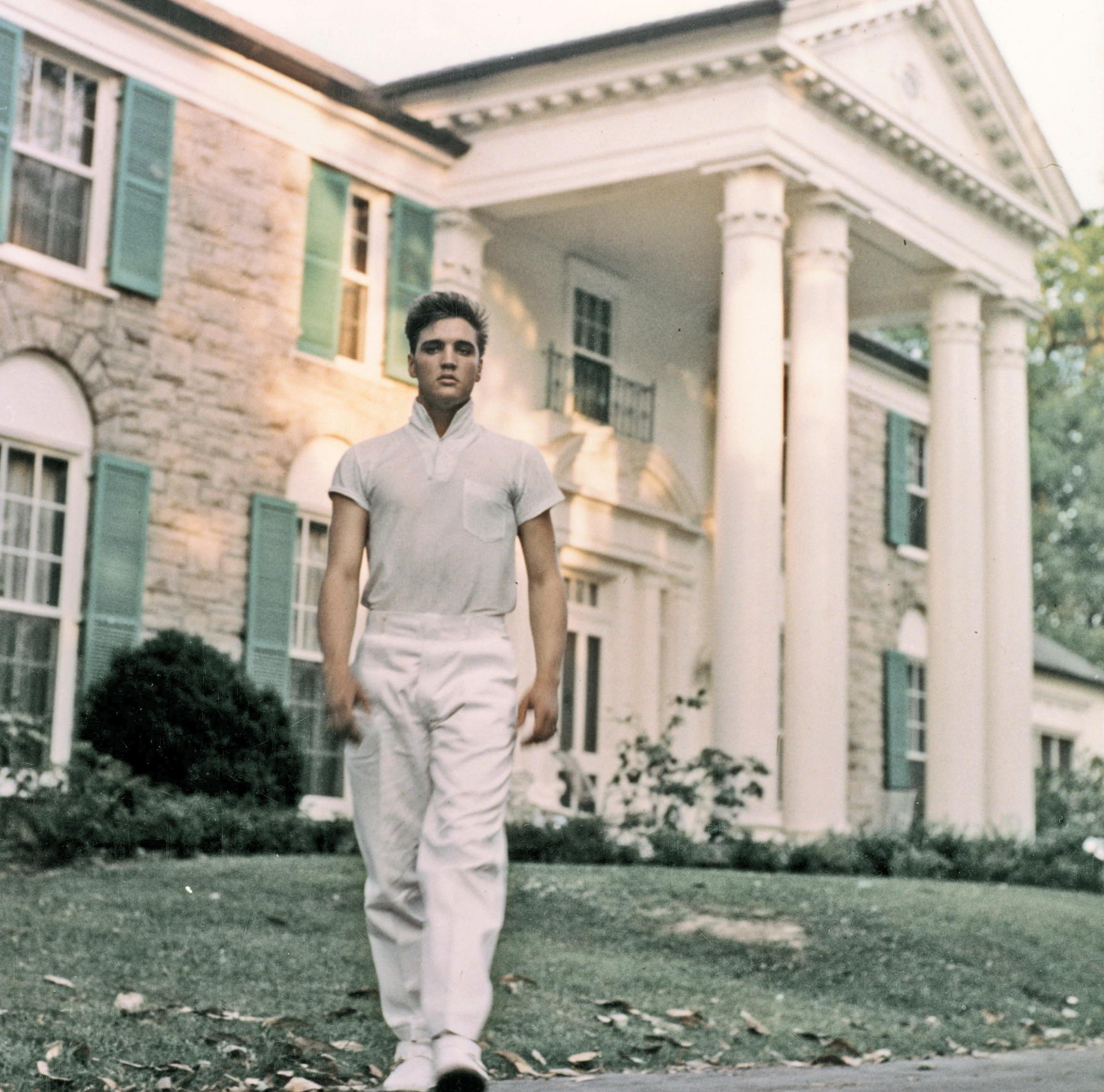 Elvis Presley standing on the grass in front of Graceland