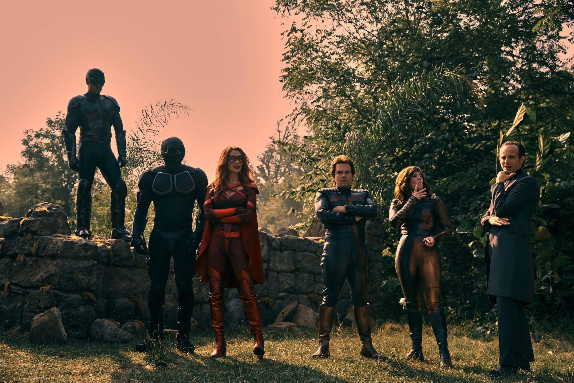 (L-R): Joel Labelle (Swatto), Nathan Mitchell (Black Noir), Laurie Holden (Crimson Countess), Jack Doolan (Tommy), Kristin Booth (Tessa), and Ryan Blakely (Mindstorm) in 'The Boys,' which could receive more spinoff series in the future. They're posing in front of trees.