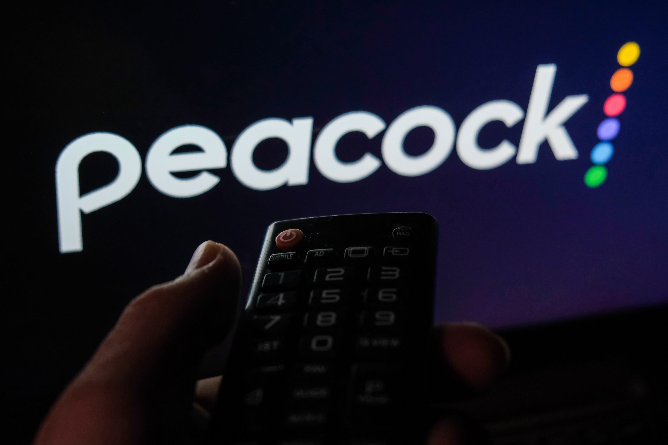 TV remote control is seen with Peacock logo displayed on a screen in this illustration photo taken in Krakow, Poland
