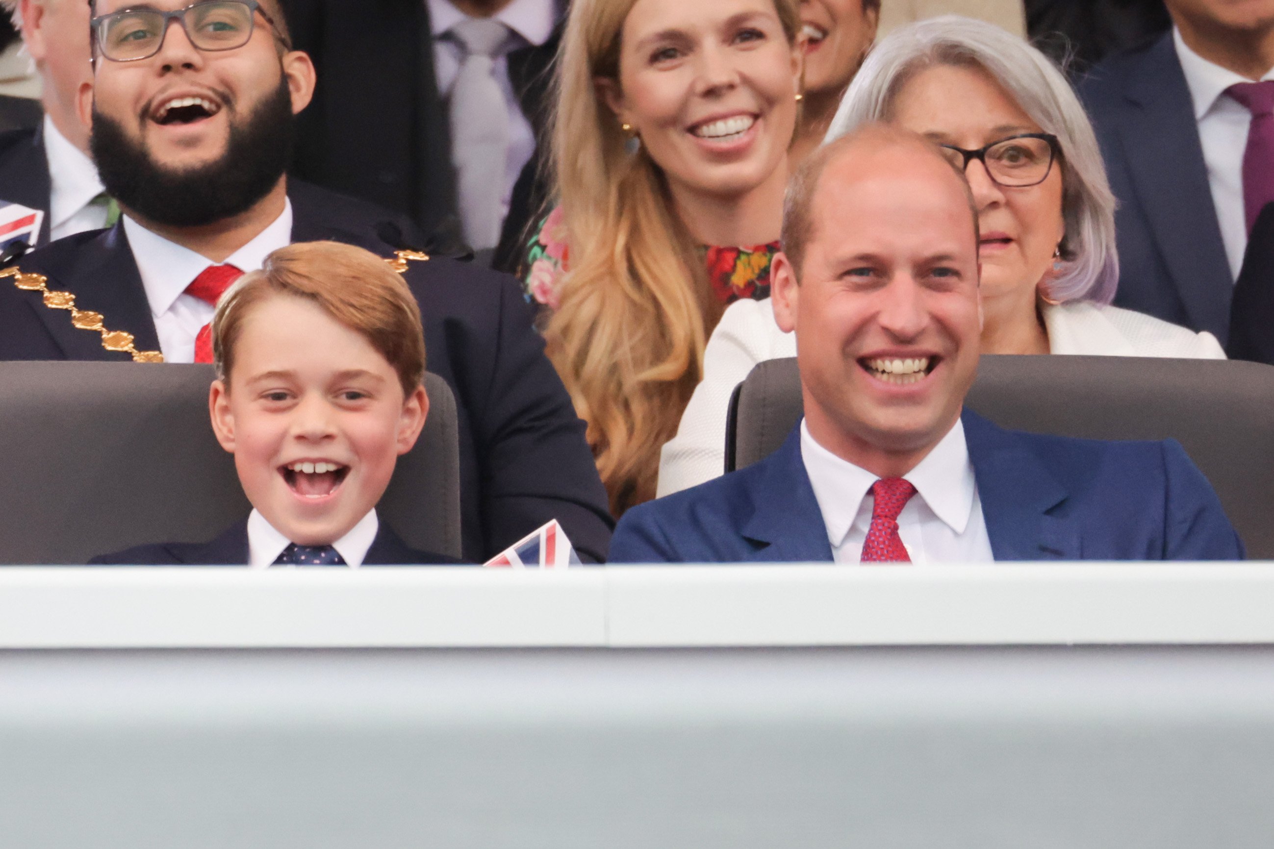 Prince George and Prince William smiling while watching the Platinum Party at the Palace concert 