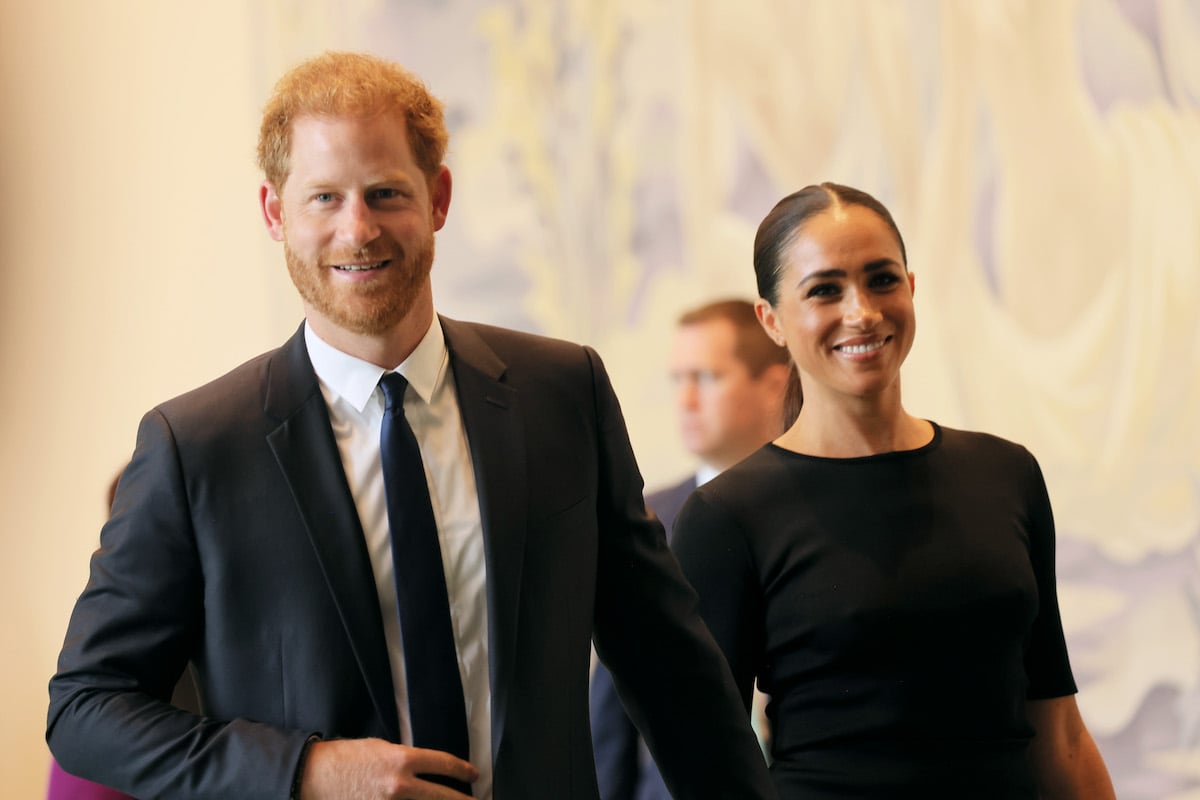 Prince Harry and Meghan Markle's body language looks supportive as they smile and hold hands at an event
