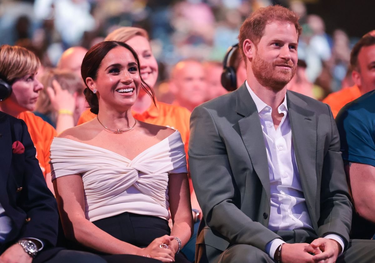 Meghan Markle and Prince Harry sit next to each other at an event.