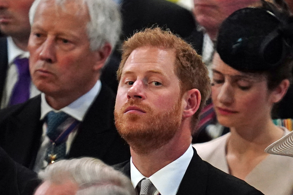 Prince Harry glances at the camera amid a crowd of people.