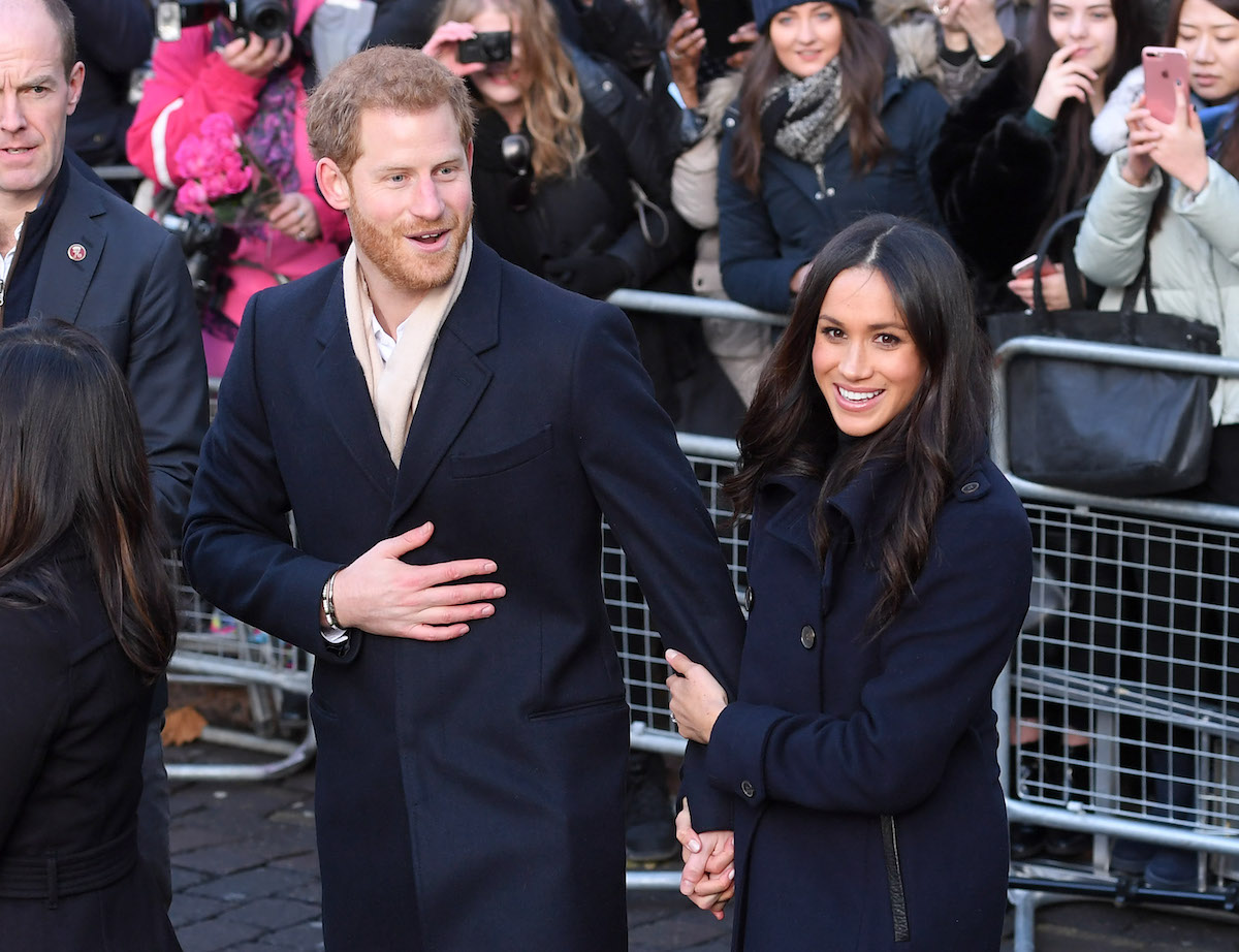 Prince Harry and Meghan Markle, who Tom Bower claims in his 'Revenge' biography believed Victoria Beckham leaked stories to the press, smile as they hold hands