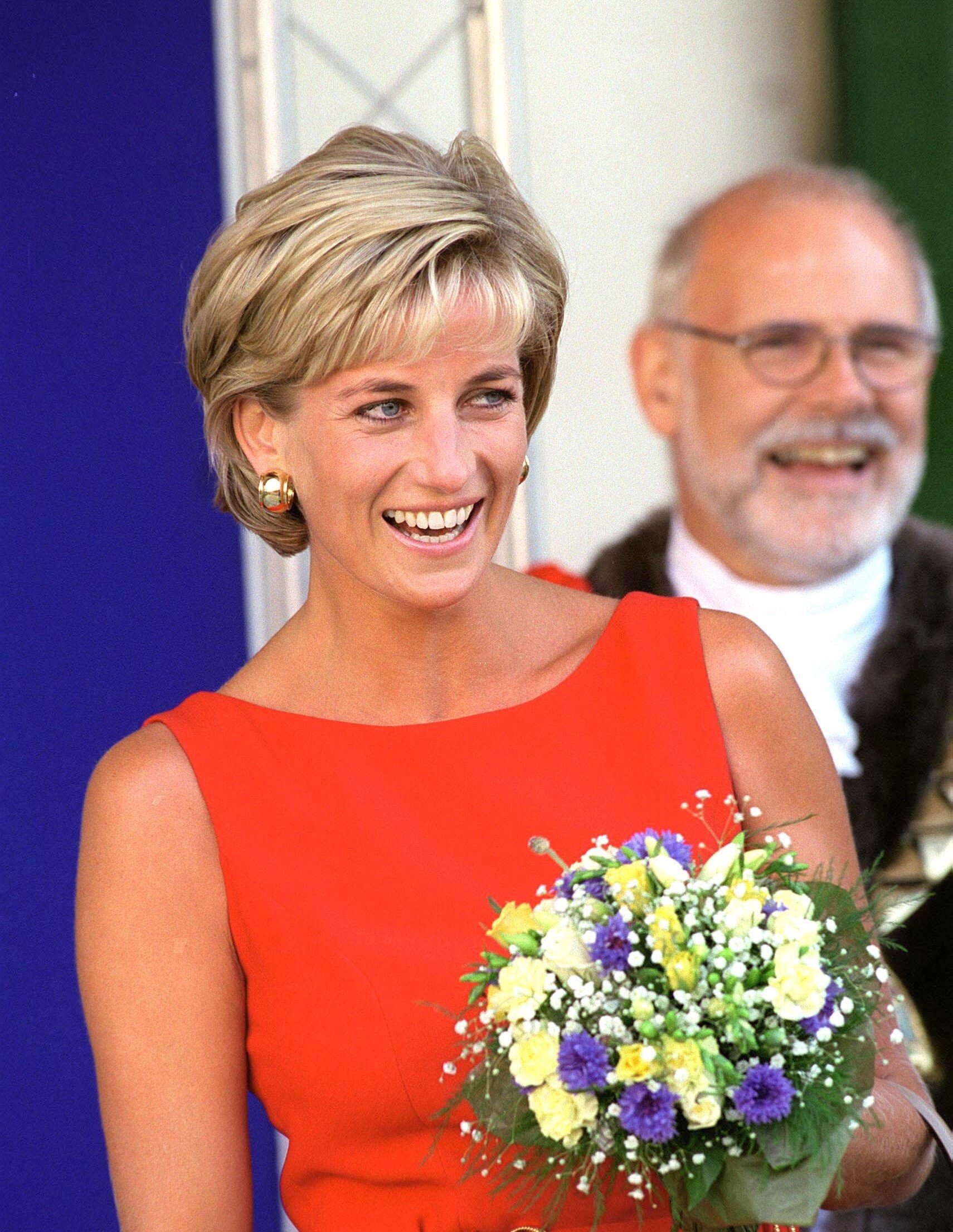 Princess Diana, who had a 'taboo' relationship with her staff, laughing while holding a bouquet of flowers during an official visit