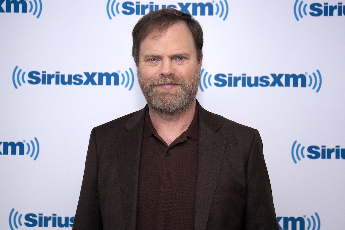 Rainn Wilson smiling in front of a blue and white background