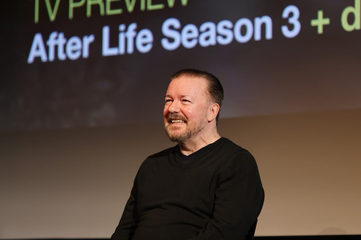 Ricky Gervais smiling while wearing a black shirt.