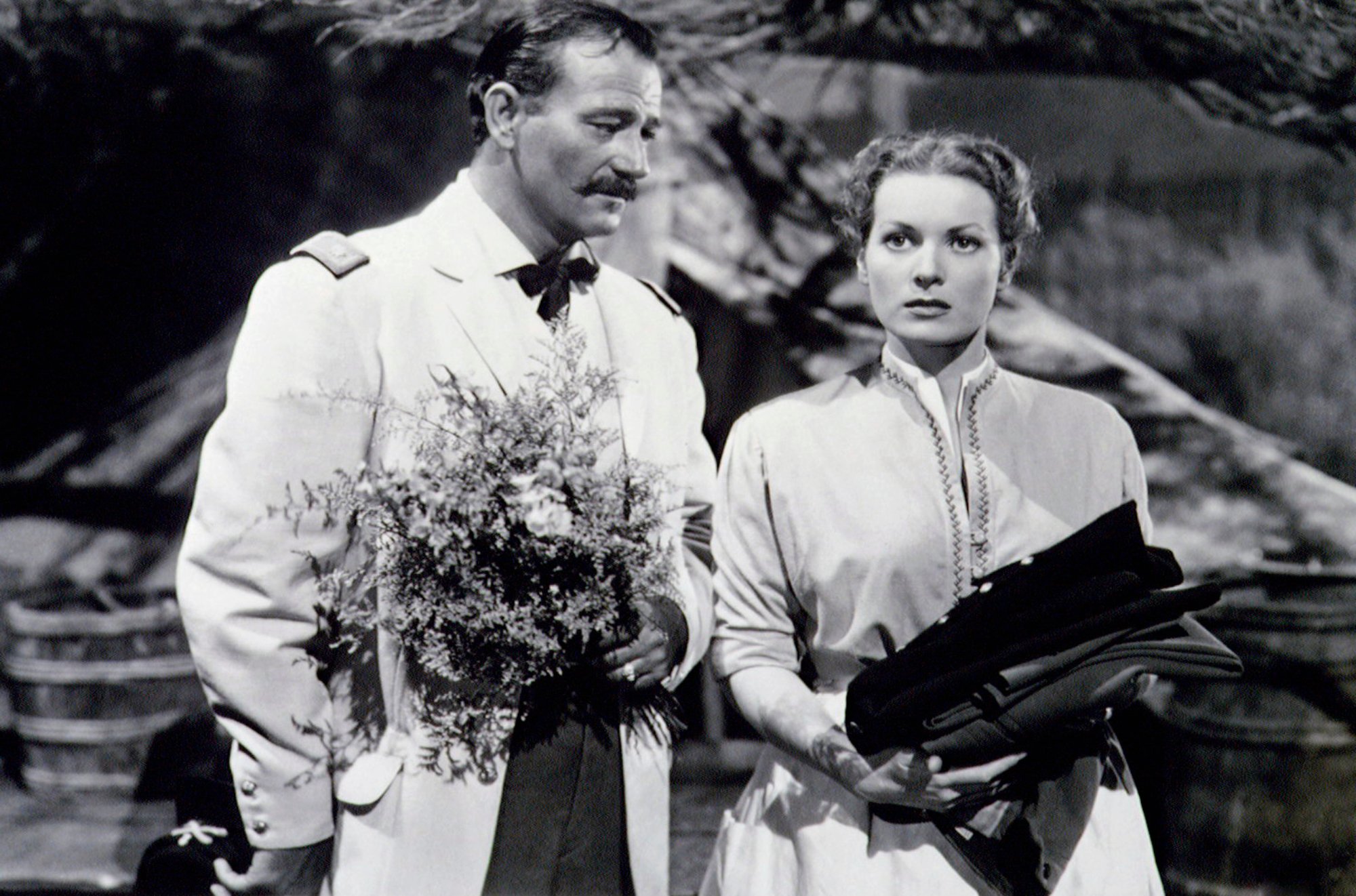 'Rio Grande' John Wayne as Lt. Col. Kirby Yorke and Maureen O'Hara as Mrs. Kathleen Yorke holding flowers and clothes with Wayne looking at O'Hara while she stares off