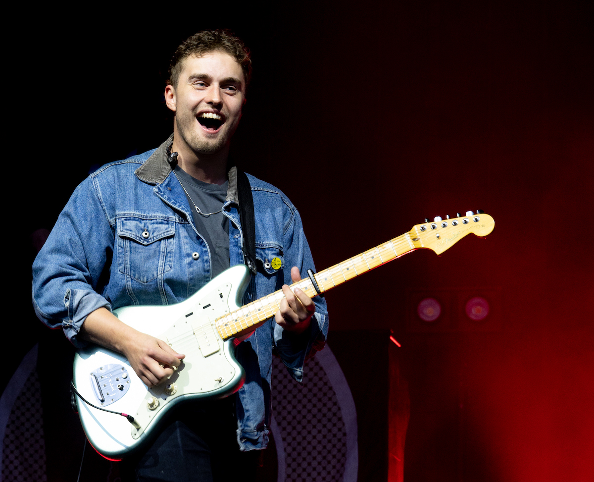 Sam Fender smiling, performing on stage