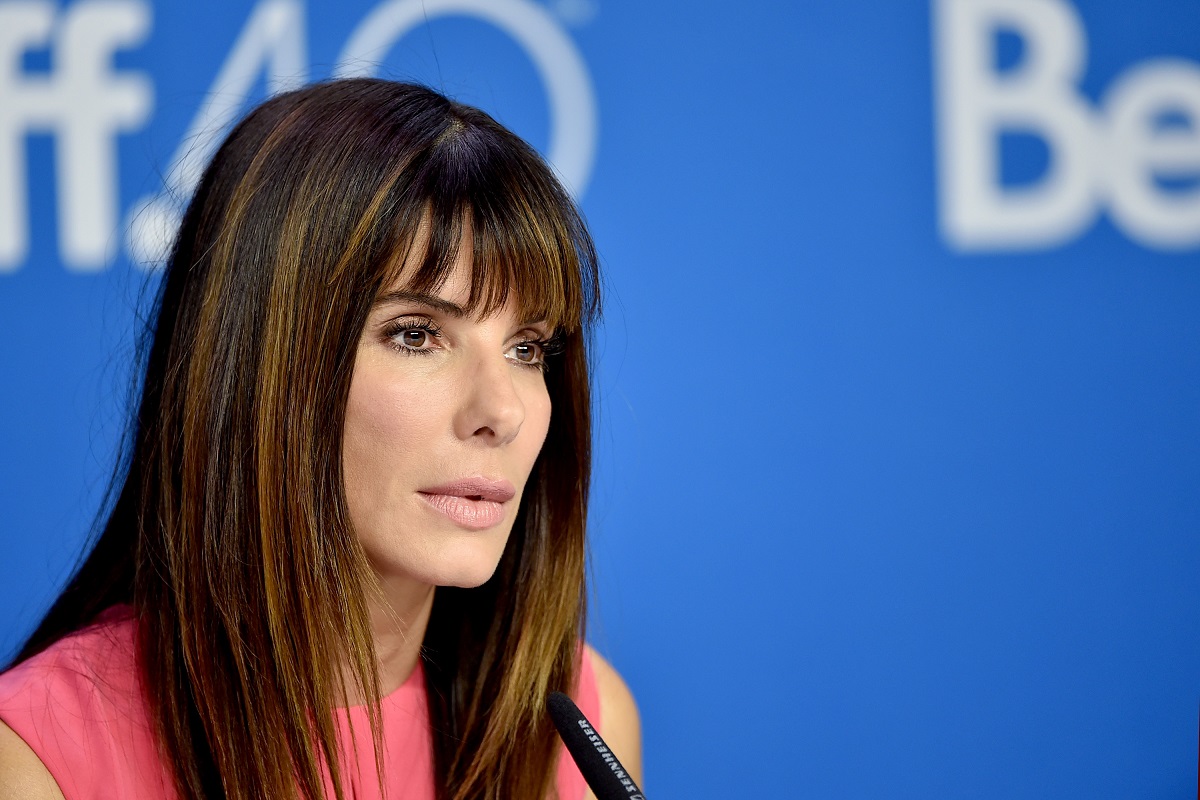 Sandra Bullock sitting down while wearing a pink shirt.