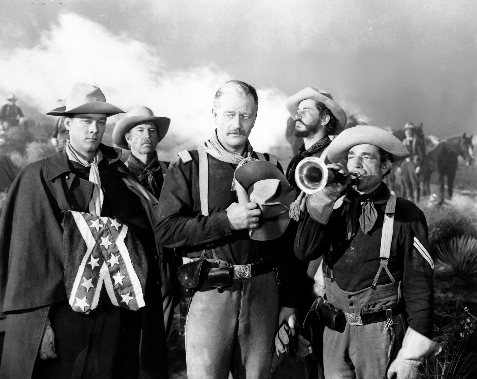 'She Wore a Yellow Ribbon' John Wayne holding a cowboy hat over his heart surrounded by men in the same hat