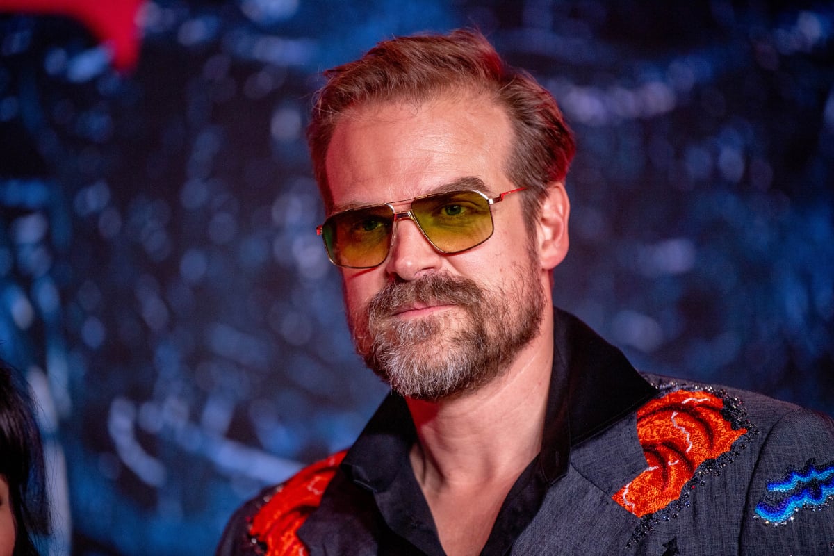David Harbour attends the Stranger Things Season 4 premiere at Netflix Brooklyn on May 14, 2022 in Brooklyn, New York. Harbour wears a patterned jacket and yellow sunglasses. 