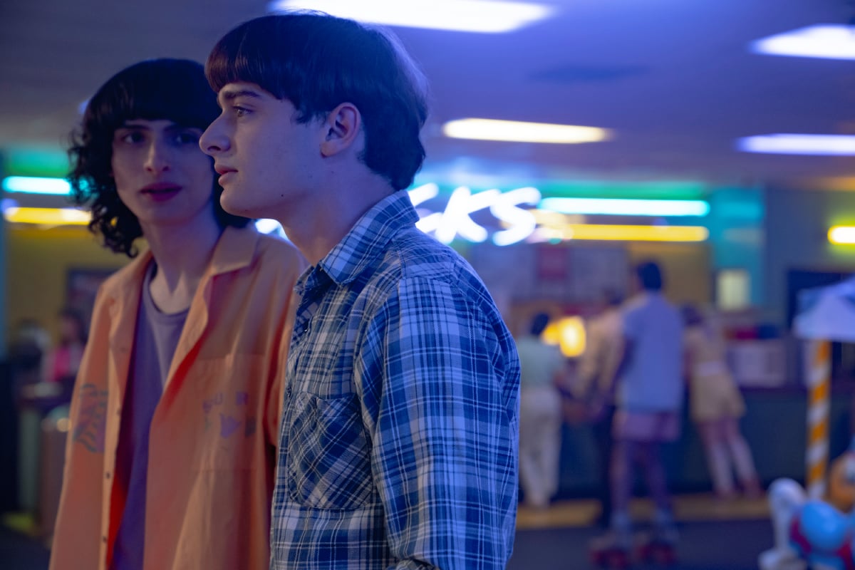 Finn Wolfhard as Mike Wheeler and Noah Schnapp as Will Byers in Stranger Things Season 4. Mike looks at Will at the skate rink. 