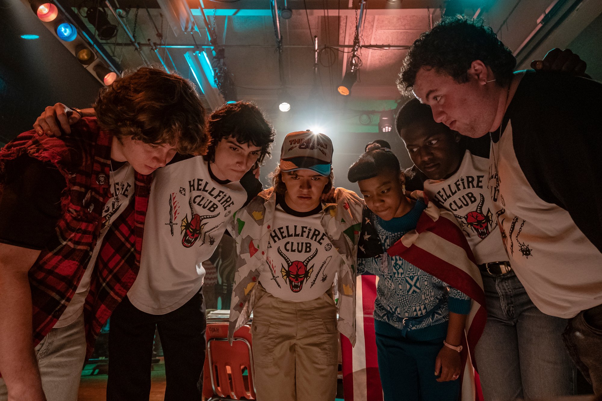 Finn Wolfhard as Mike Wheeler, Gaten Matarazzo as Dustin Hendrson and Priah Ferguson as Erica Sinclair in 'Stranger Things,' which has already received a season 5 renewal. The characters are huddled with several older boys from the Hellfire Club.