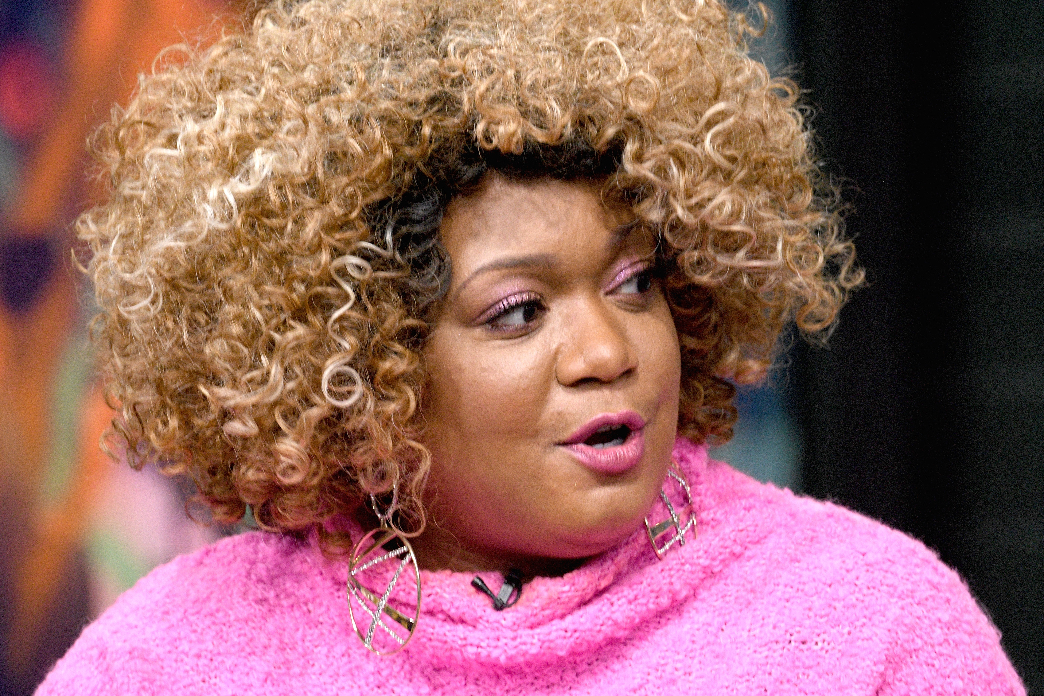 Food Network star Sunny Anderson wears a pink sweater in this photograph.