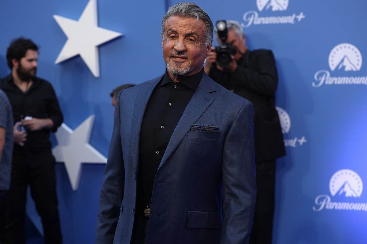 Sylvester Stallone posing while wearing a blue and black suit.