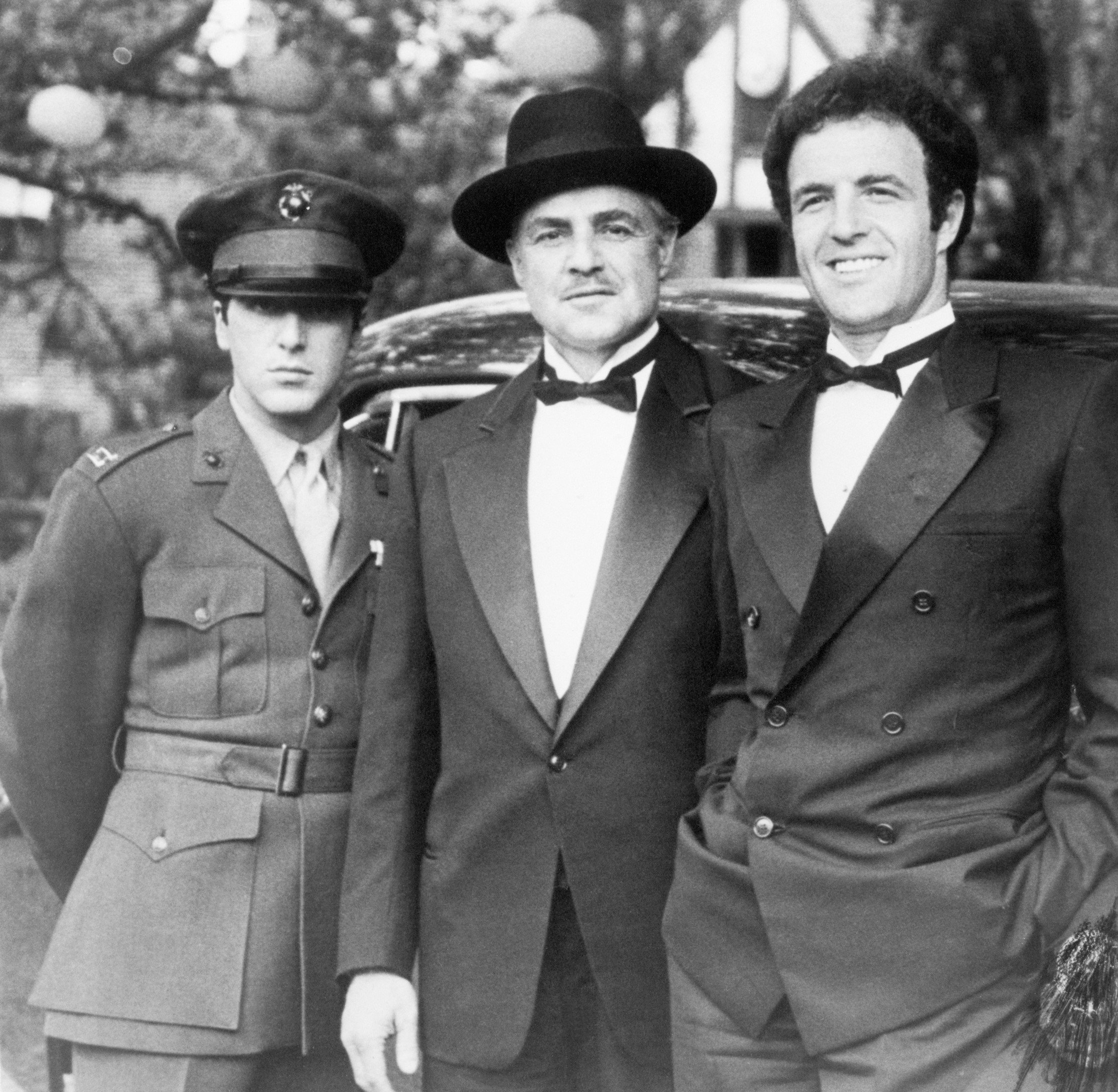 A black and white picture of Al Pacino, Marlon Brando, and James Caan on the set of 'The Godfather.'