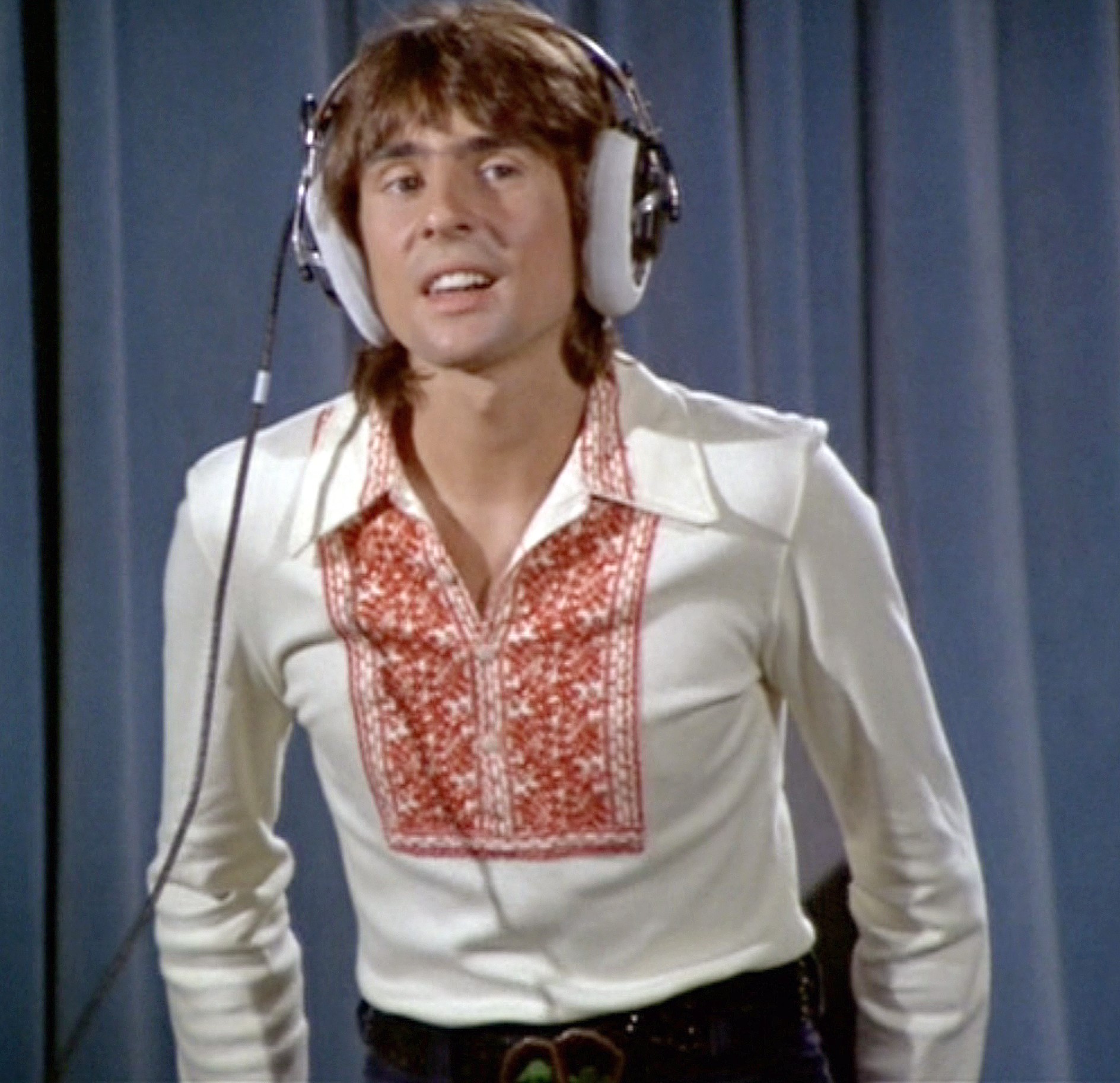 The Monkees' Davy Jones in front of a blue curtain