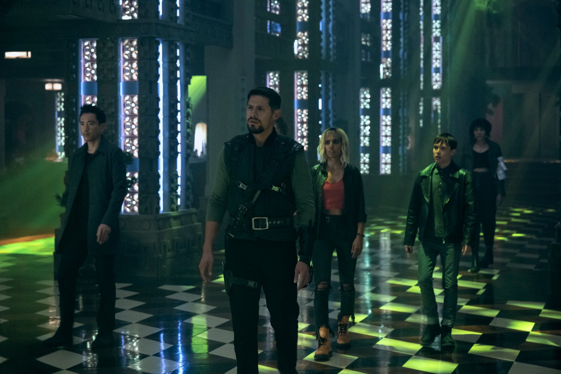 Justin H. Min as Ben Hargreeves, David Castañeda as Diego Hargreeves, Ritu Arya as Lila Pitts, Elliot Page as Viktor Hargreeves, and Emmy Raver-Lampman as Allison Hargreeves in 'The Umbrella Academy,' which has not been renewed for season 4 yet. The group is standing in a dark room with a checkered floor. They all look perplexed.