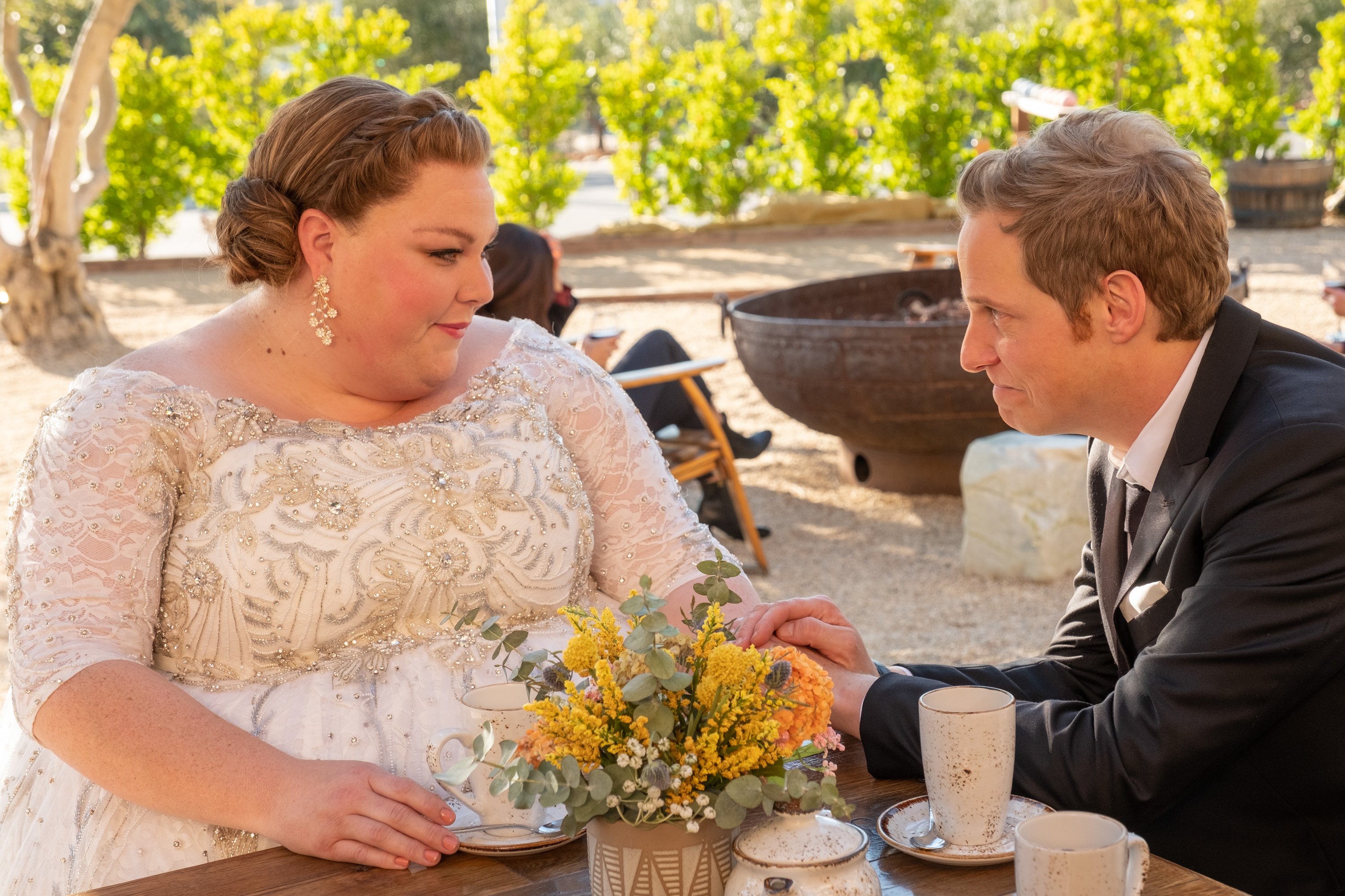 Chrissy Metz and Chris Geere, in character as Kate and Phillip in 'This Is Us' Season 6, share a scene on their wedding day. Kate wears a sparkly white wedding dress. Phillip, who is holding Kate's hand, wears a black suit.