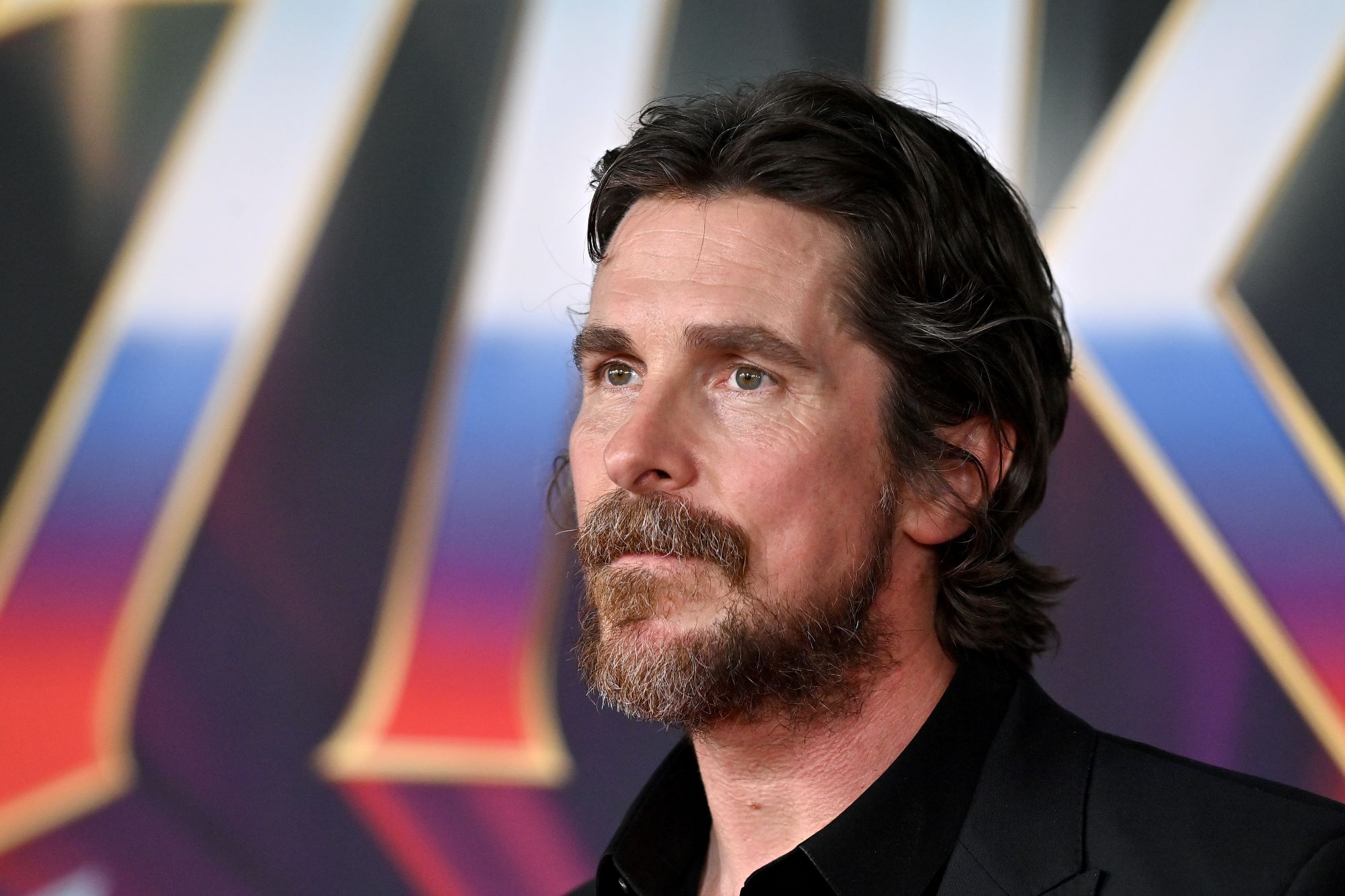Christian Bale, who played Gorr the God Butcher in 'Thor: Love and Thunder,' wears a black suit over a black button-up shirt.