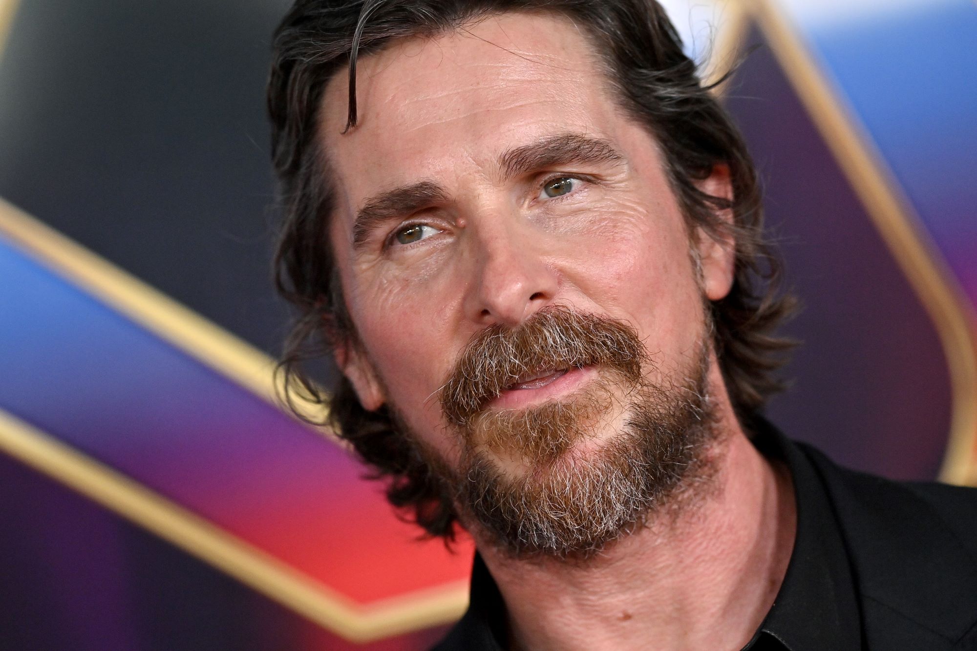 Christian Bale, whose character Gorr loses his daughter in 'Thor: Love and Thunder,' wears a black suit.